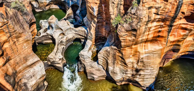 Cylindrical potholes and sculpted red rock channels at Bourke's Luck Potholes, Mpumalanga