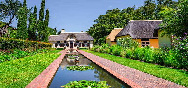 Thatched Cape Dutch buildings and the long lily pond in the gardens at Vergelegen, Cape Winelands