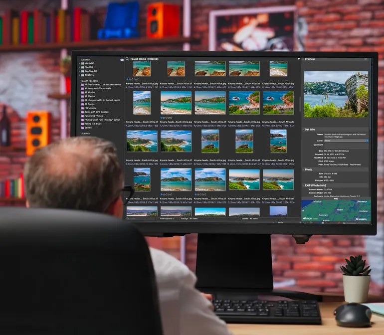Photographer reviewing a grid of Knysna Heads photographs in a photo library on a large monitor