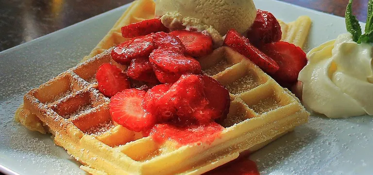 A Brussels-style Belgian waffle dusted with icing sugar, served with strawberries, whipped cream and vanilla ice cream