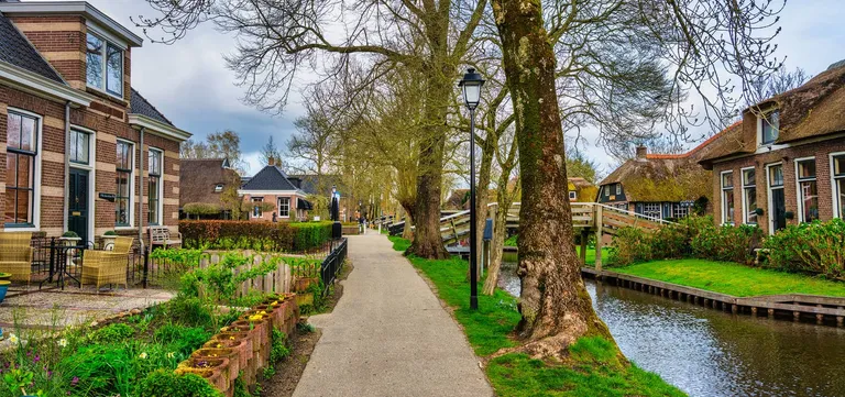 The tree-lined Binnenpad footpath running between houses and the canal in Giethoorn