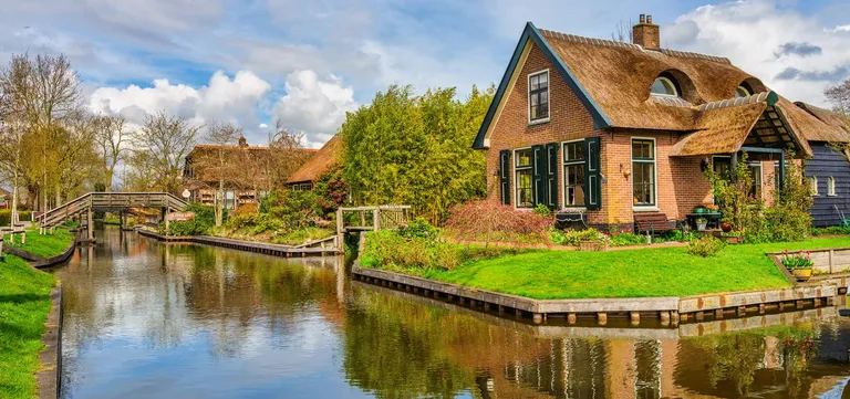 A quiet Giethoorn canal lined with thatched cottages and gardens