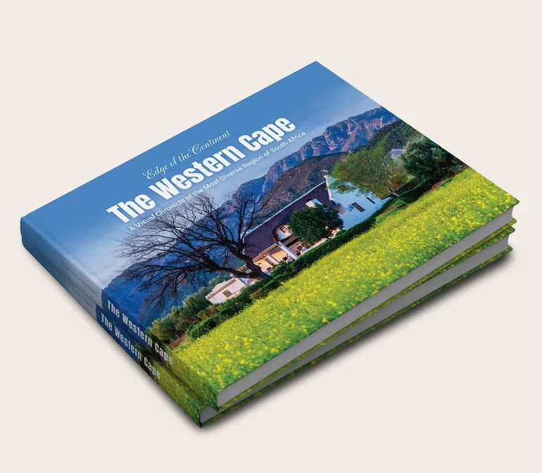 Stacked hardcover copies of Edge of the Continent: The Western Cape, a large-format photographic book on South Africa
