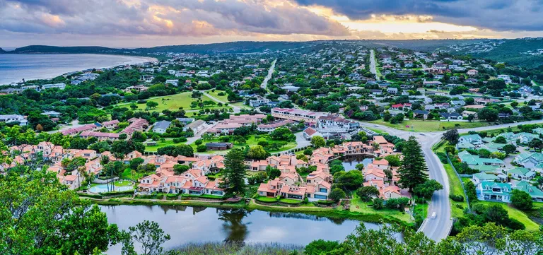 Plettenberg Bay's homes and gardens rolling down green hills toward the beach and lagoon, South Africa