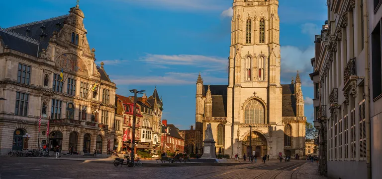 The Gothic west front and tower of Saint Bavo's Cathedral on Sint-Baafsplein, Ghent, in late afternoon light