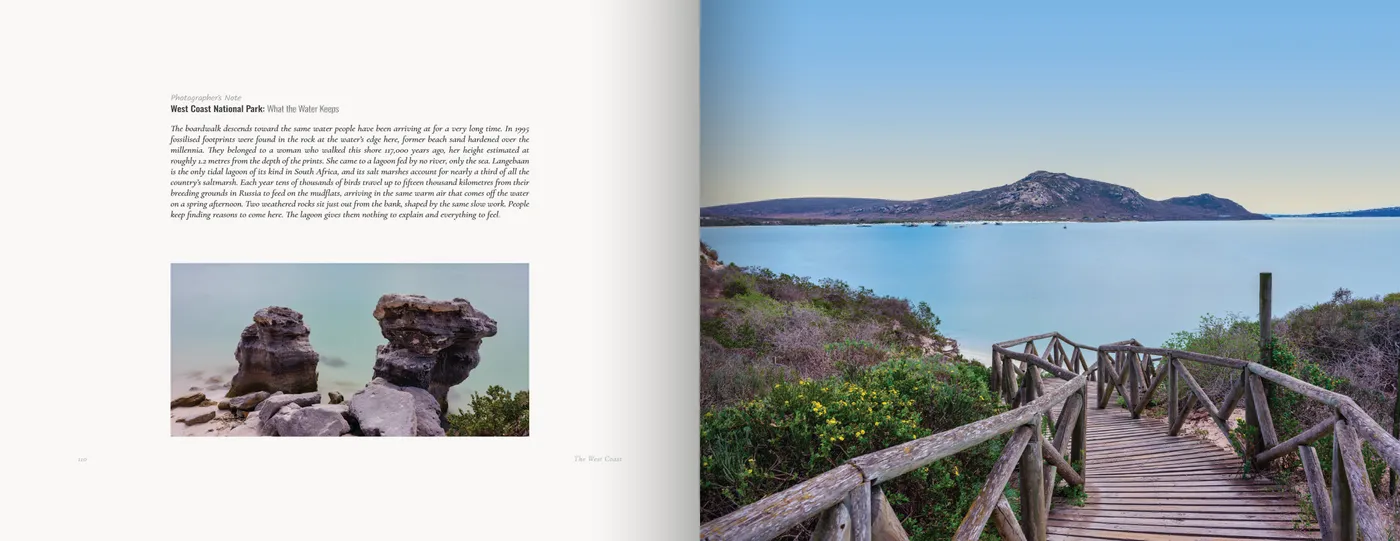 The note and two weathered rock stacks in shallow water face a boardwalk descending to a blue lagoon