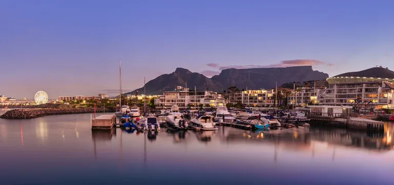 V&A Waterfront harbour illuminated after sunset with Table Mountain behind, Cape Town