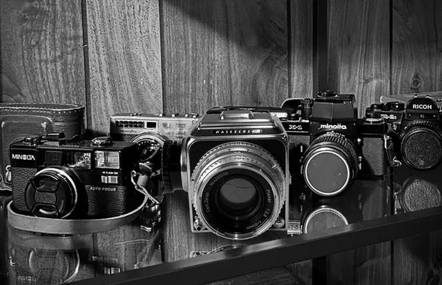 Five film cameras on a wooden shelf, the 1998 Hasselblad at the centre